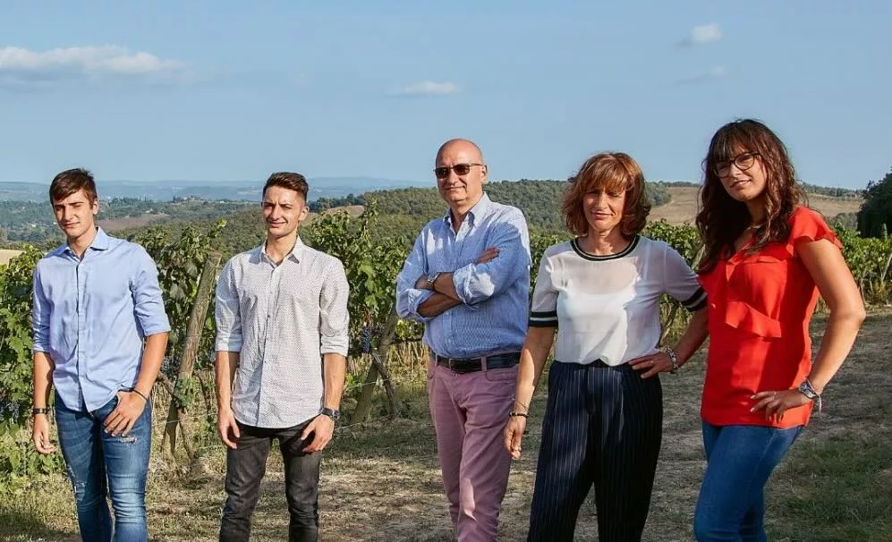 Familie Ravazzi poserend in hun wijngaard bij Palazzone, San Casciano dei Bagni in zuidelijk Toscane, met uitzicht op de heuvels.