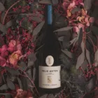 Baron Longo Felix Anton Lagrein fles tussen alpine bloemen en takken in het Trudner Horn Natuurpark, Zuid-Tirol